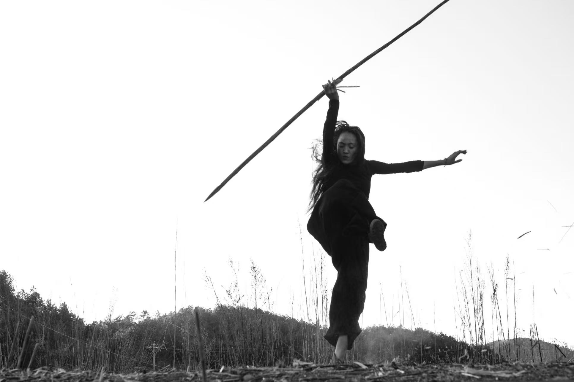 Black-and-white outdoor dancer balancing with a long pole