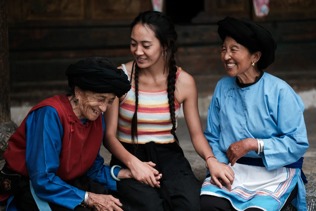 董继兰与两位女性坐在木屋前交谈