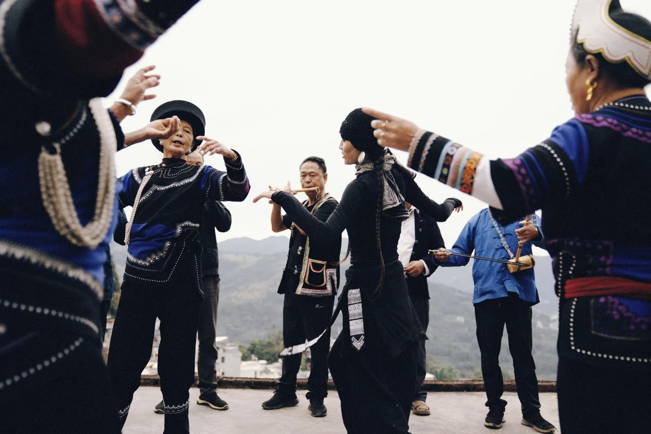 身着民族服饰的人们围成一圈交流动作