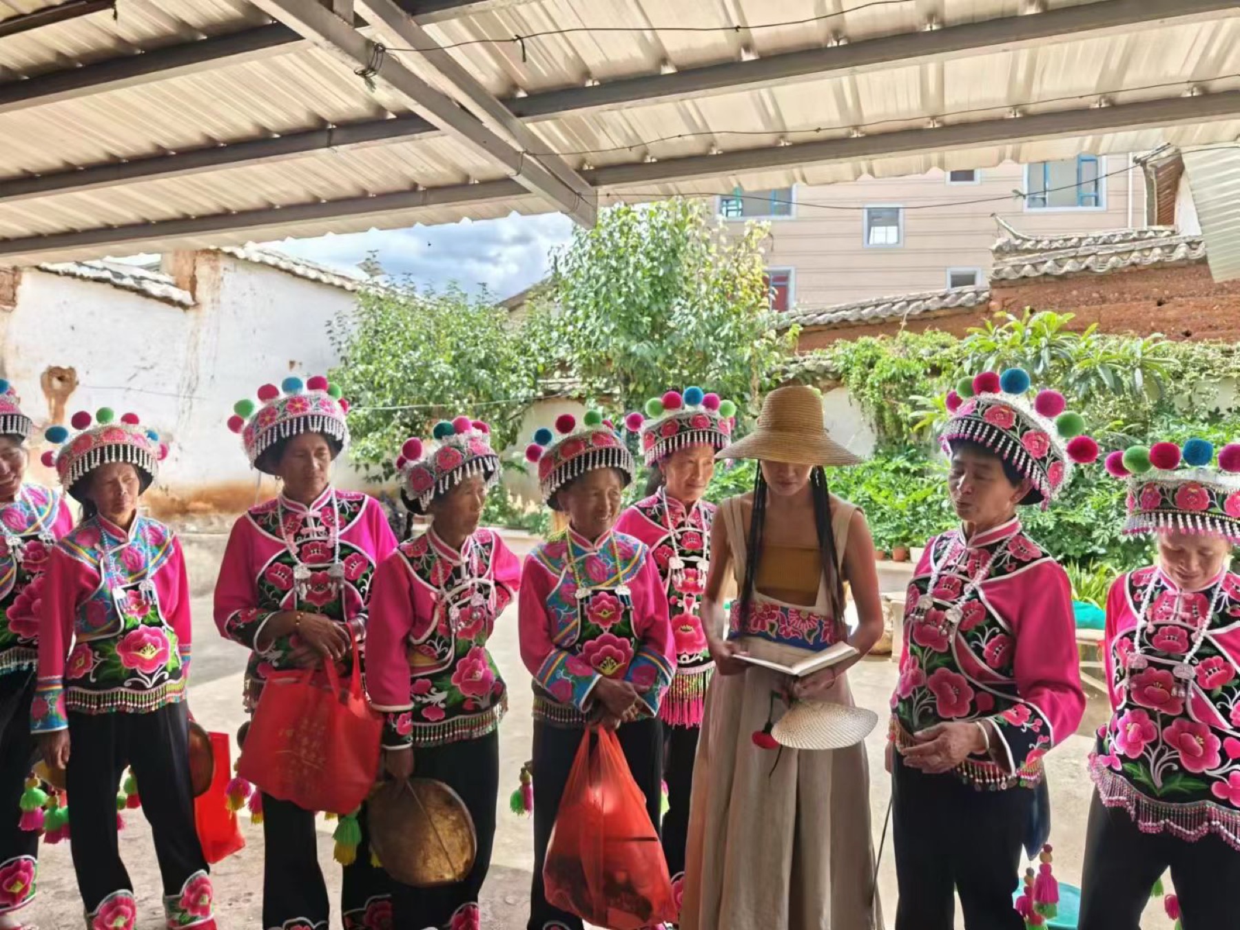 董继兰与身穿民族服饰的传承人站在村寨院落中